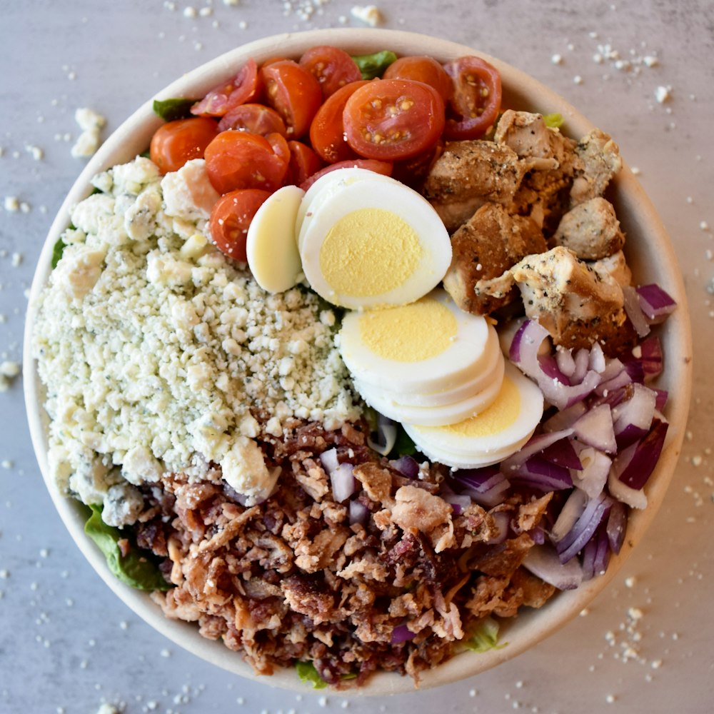 a salad with hard boiled eggs, tomatoes, onions, and other ingredients