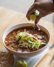 a bowl of chili with a lime on top of it