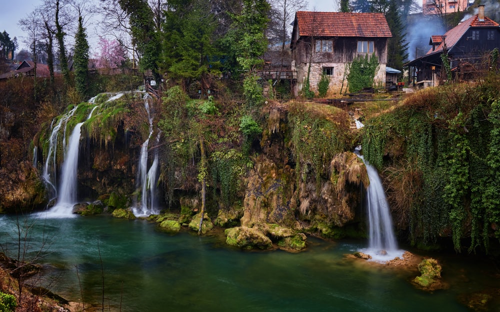 a waterfall with a house in the background