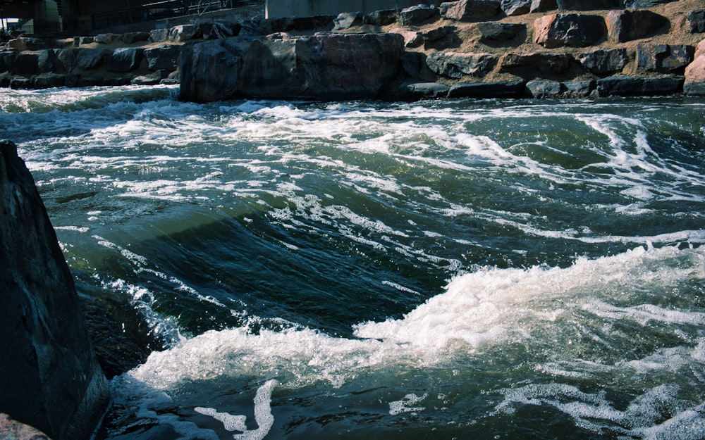 a man standing on top of a rock next to a river