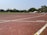 A well-maintained athletic track with clear lane markings under a bright blue sky.