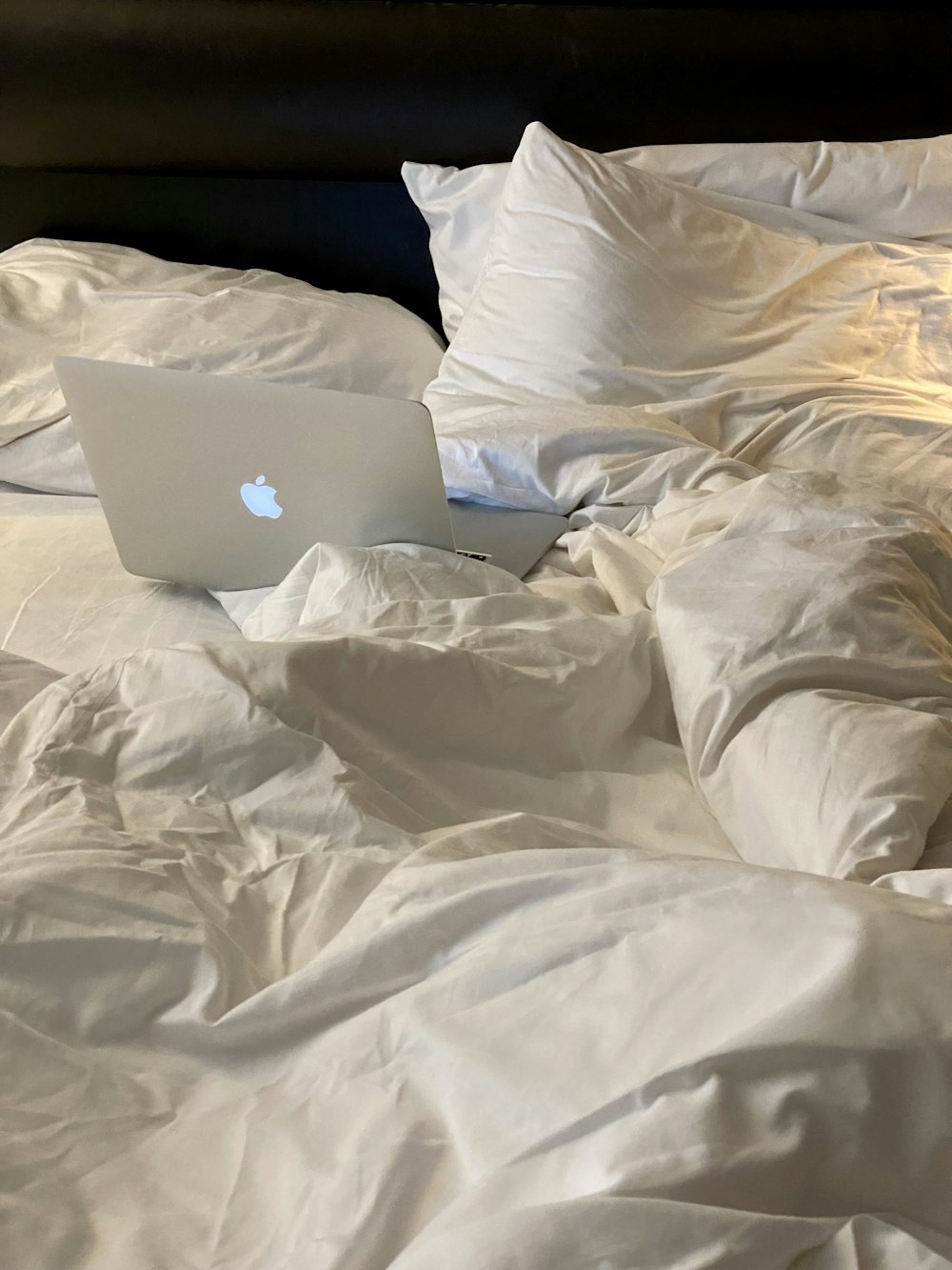 an apple laptop sitting on top of a bed