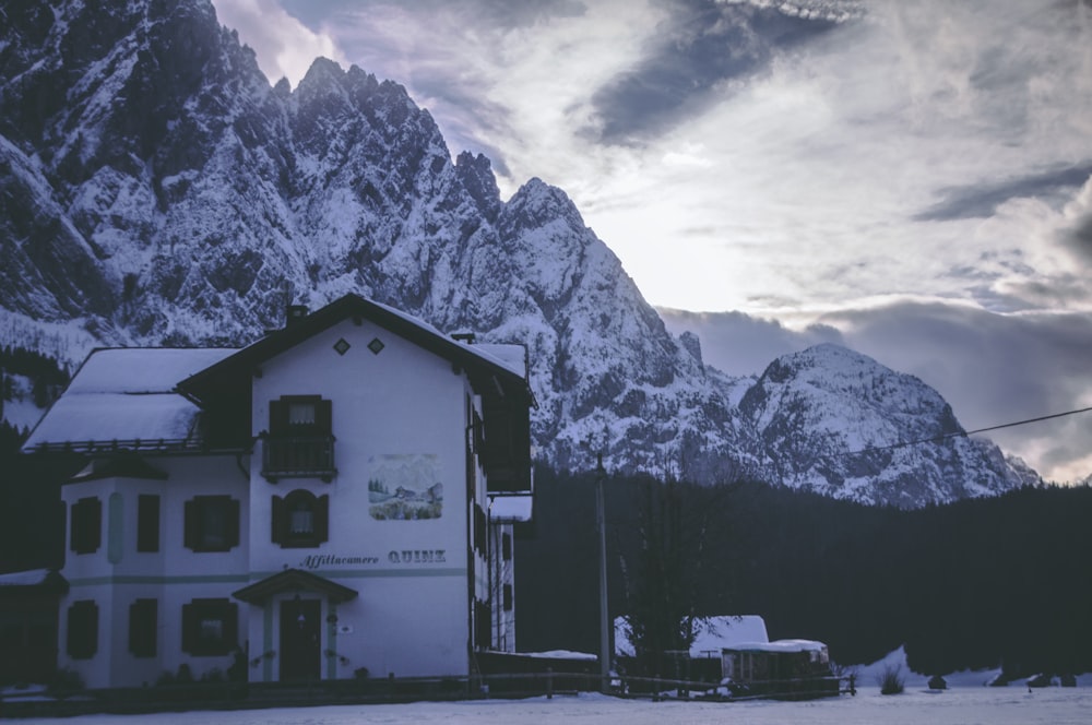 a snow covered mountain side with a building in the foreground