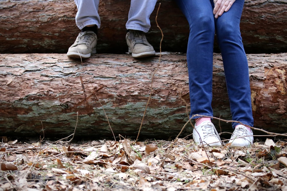 two people sitting on a log in the woods