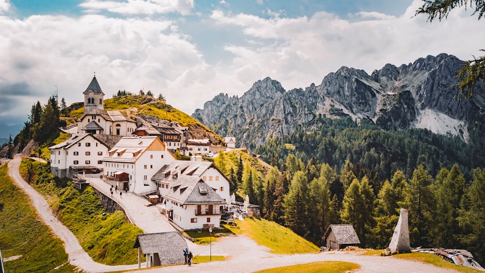 a small village on a hill with mountains in the background