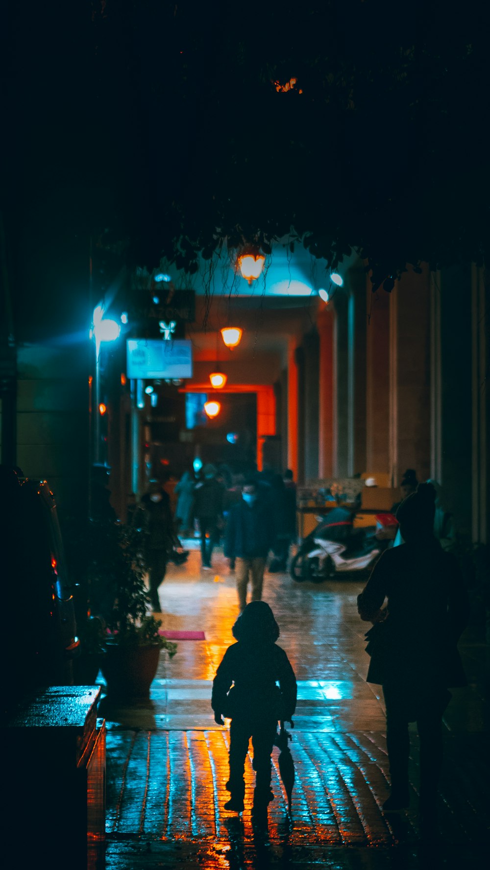 a couple of people walking down a street at night