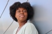 a young black woman leaning against a wall