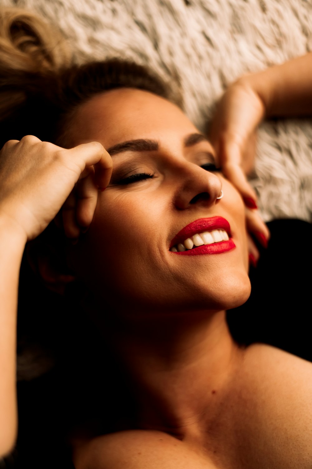 a beautiful woman laying on top of a white rug