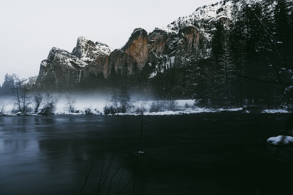 a mountain covered in snow next to a body of water