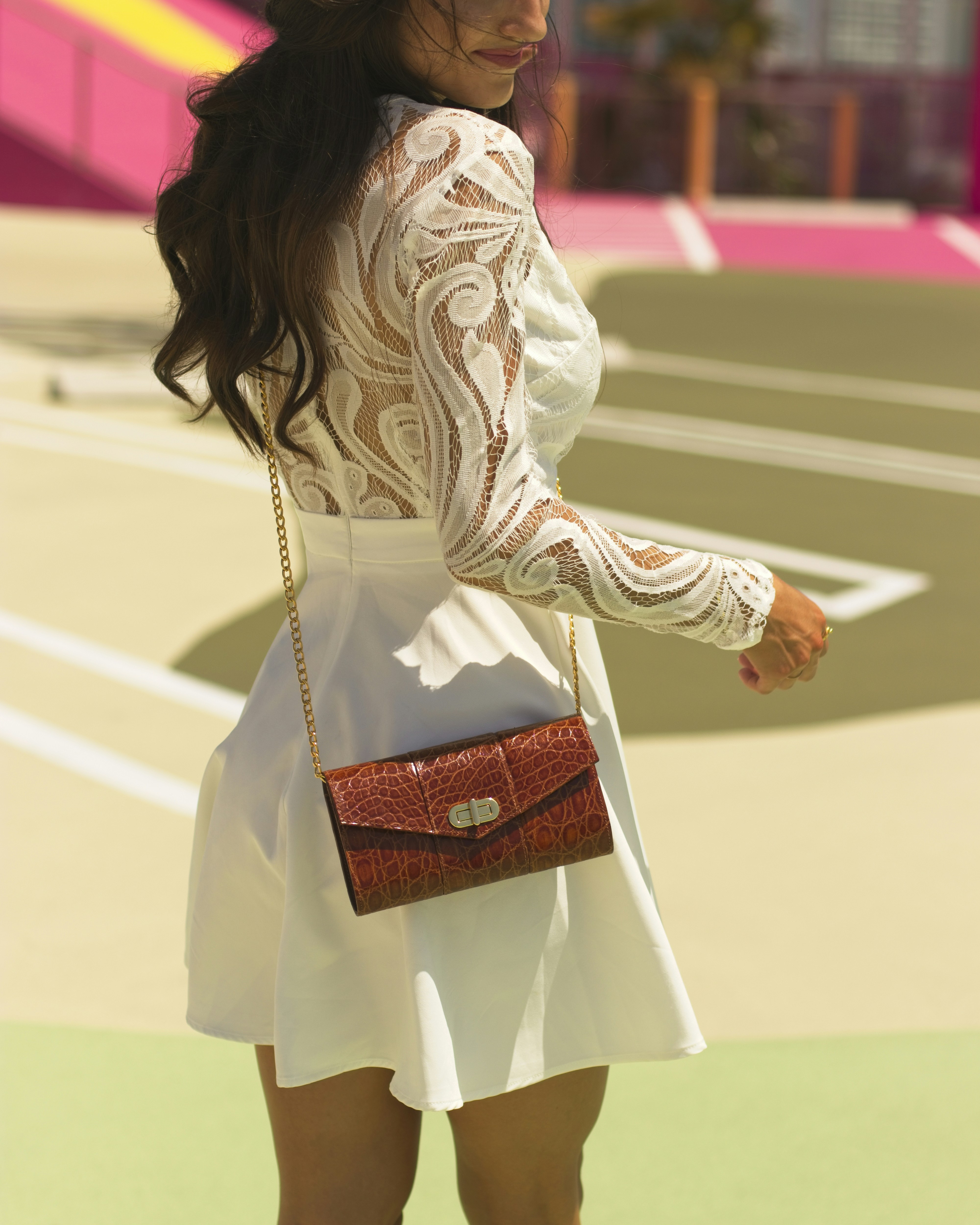 a woman in a white dress holding a brown purse