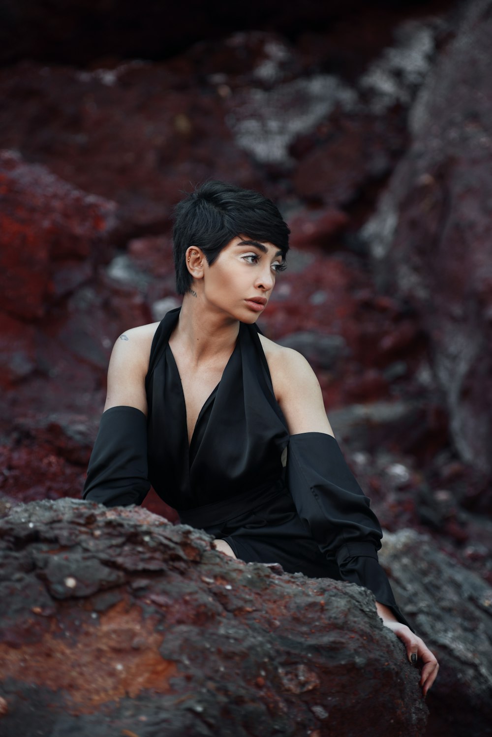 a woman in a black dress sitting on a rock