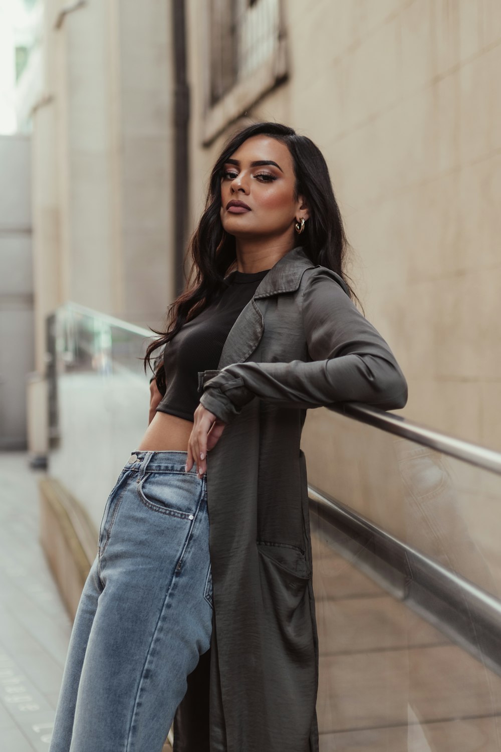 a woman leaning against a rail wearing jeans