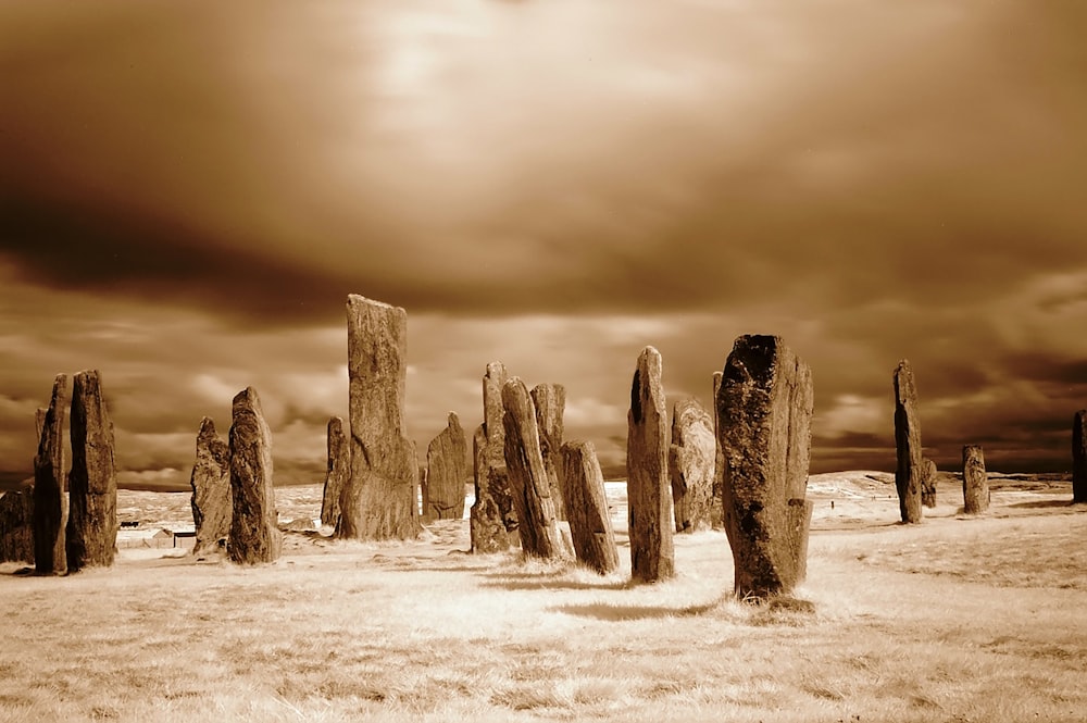 a group of rocks in a field under a cloudy sky