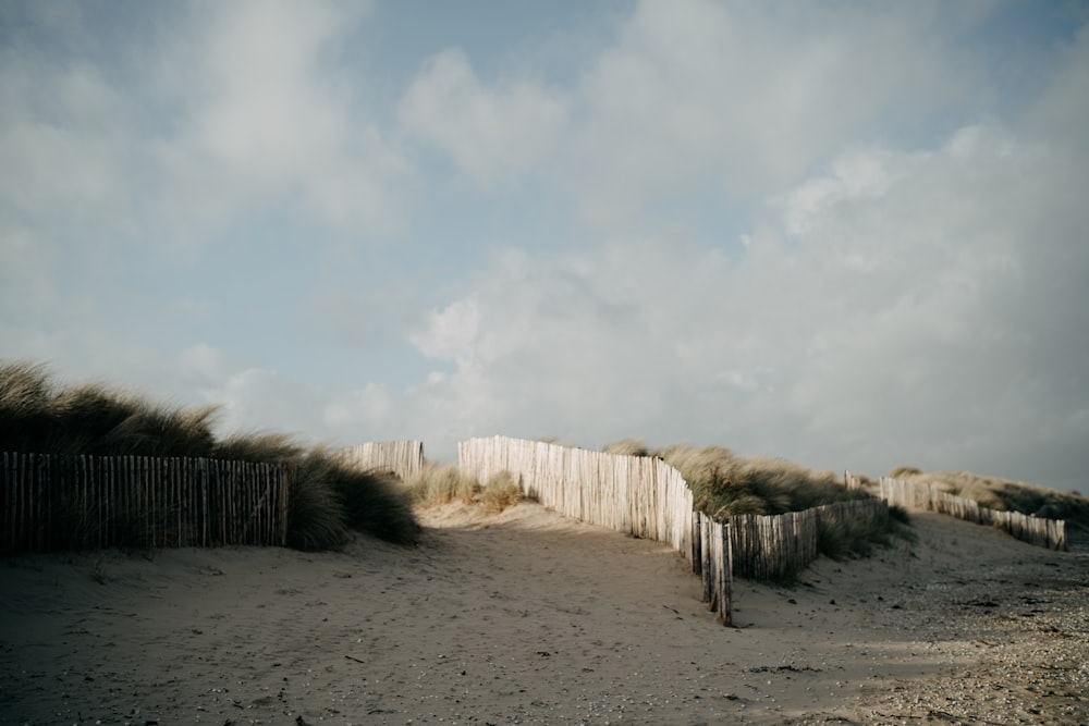 a sandy beach with a fence and sand dunes