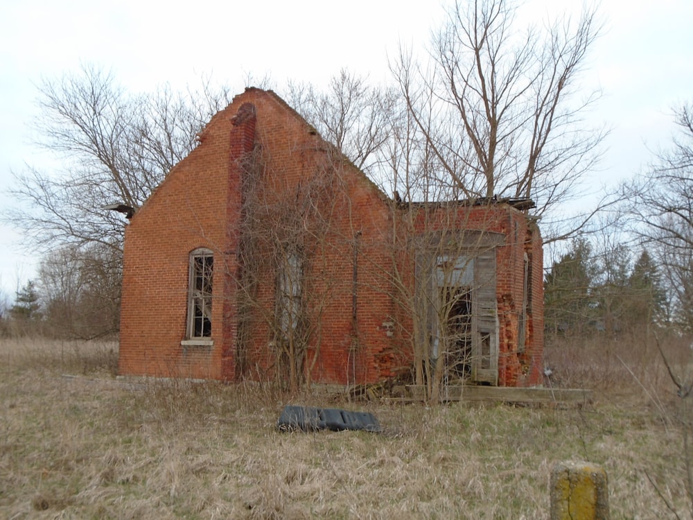 an old red brick building sitting in a field