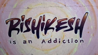 Graffiti-style mural on a wall with the text 'Rishikesh is an Addiction'. The background features circular patterns in pastel colors.