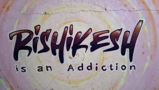 Graffiti-style mural on a wall with the text 'Rishikesh is an Addiction'. The background features circular patterns in pastel colors.