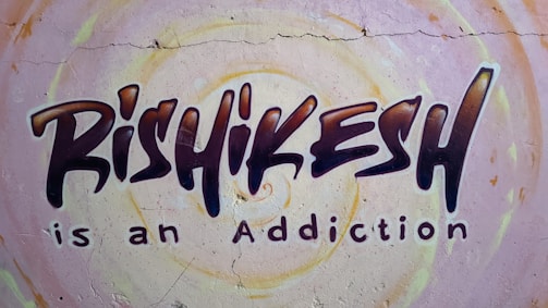 Graffiti-style mural on a wall with the text 'Rishikesh is an Addiction'. The background features circular patterns in pastel colors.