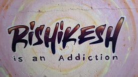 Graffiti-style mural on a wall with the text 'Rishikesh is an Addiction'. The background features circular patterns in pastel colors.