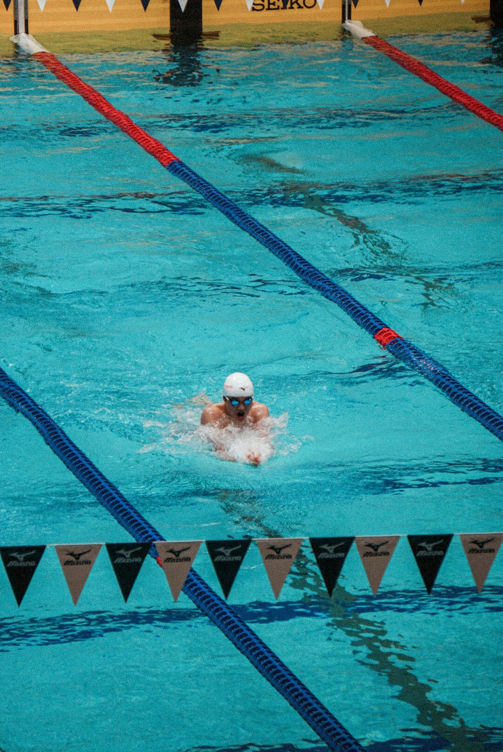a man swimming in a pool with a white cap