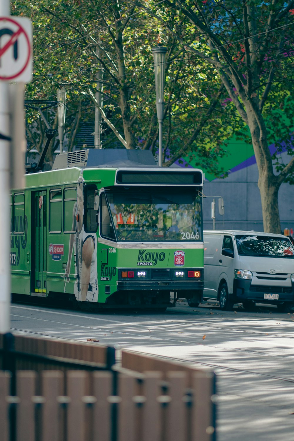 a green bus driving down a street next to a traffic light
