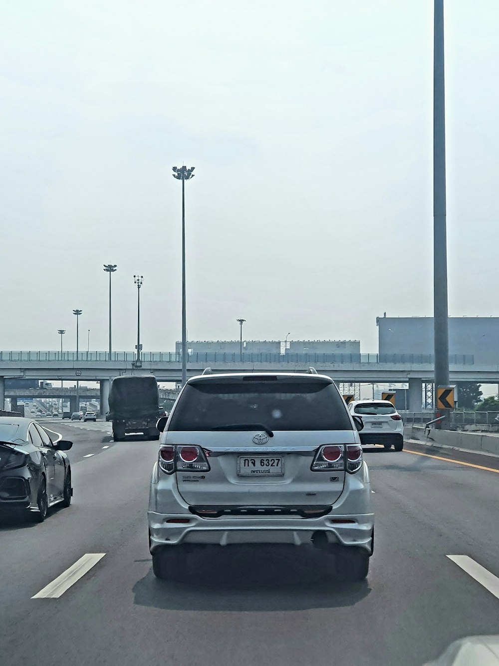 a white car driving down a highway next to a bridge