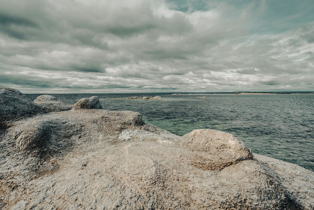 a large body of water sitting next to a rocky shore