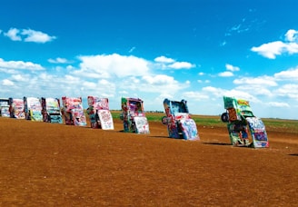 a row of parked cars sitting on top of a dirt field