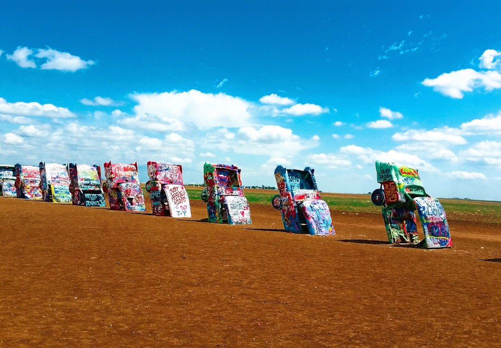 a row of parked cars sitting on top of a dirt field