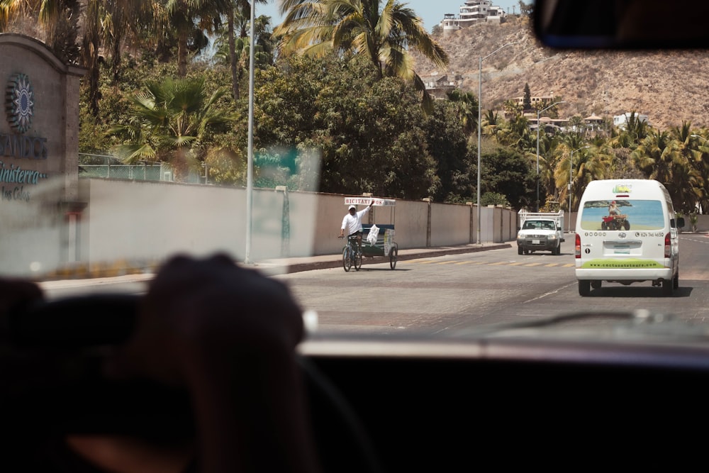 a man riding a motorcycle down a street next to a white van