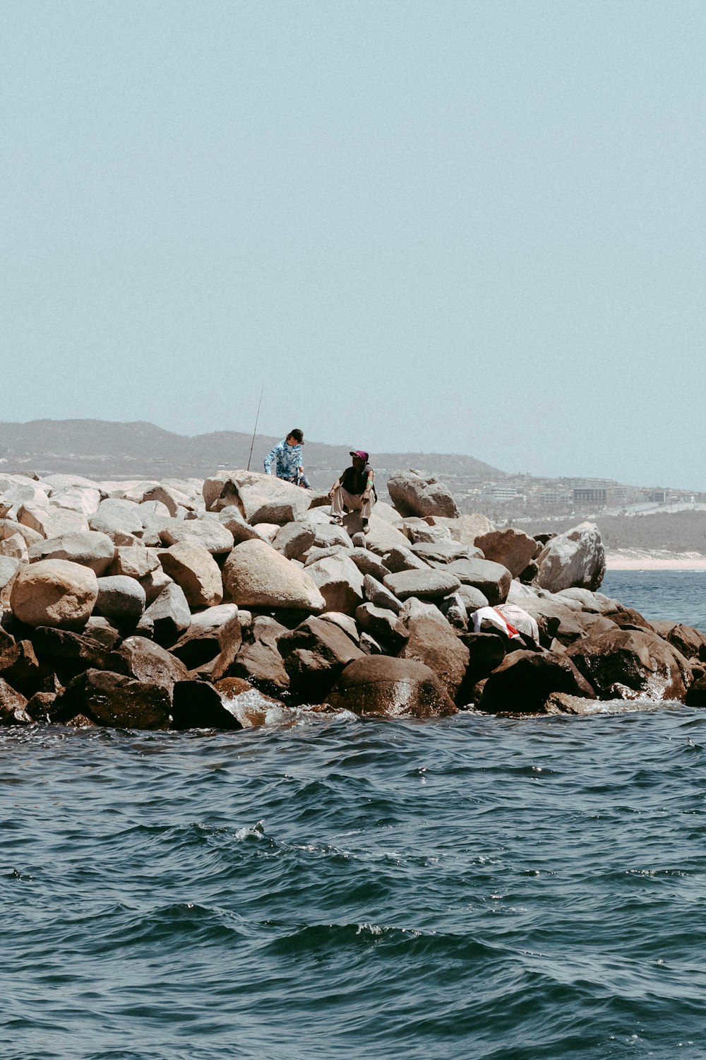 a couple of people standing on top of a rocky shore