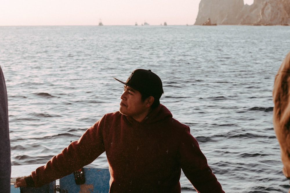 a man holding a skateboard standing next to a body of water