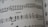 A close-up of a sheet of printed music featuring musical notes and symbols on a staff line. The term 'cresc.' appears, indicating a crescendo. The paper appears to curve slightly, suggesting the image captures a part of an open book.