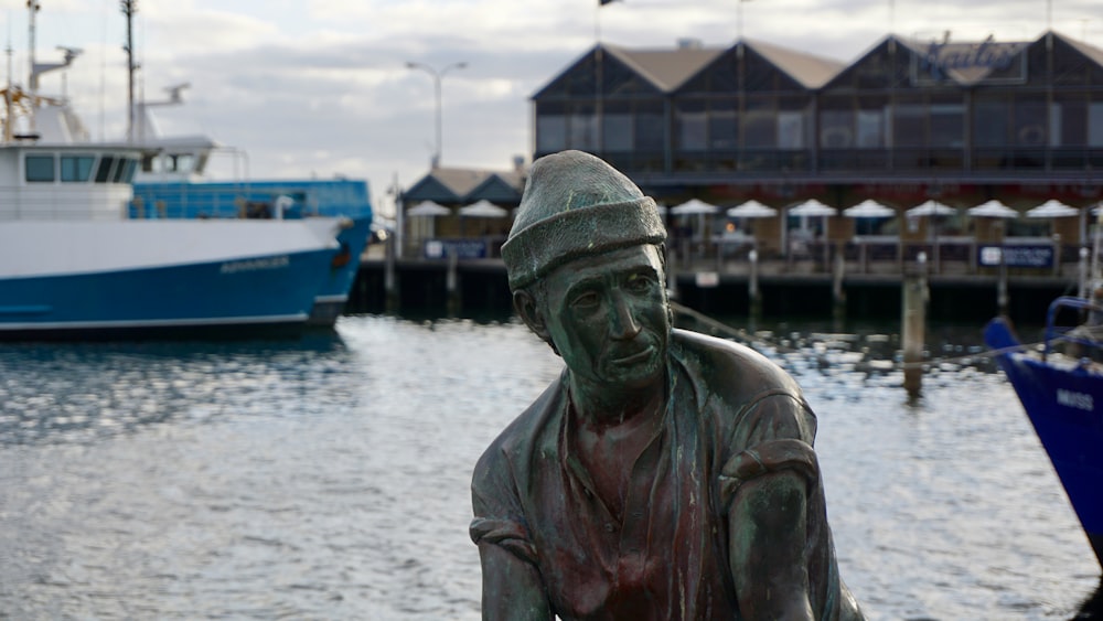 a statue of a man sitting next to a body of water