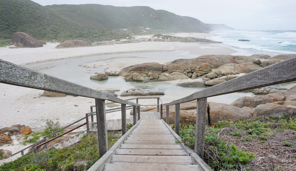 a wooden staircase leading to a sandy beach