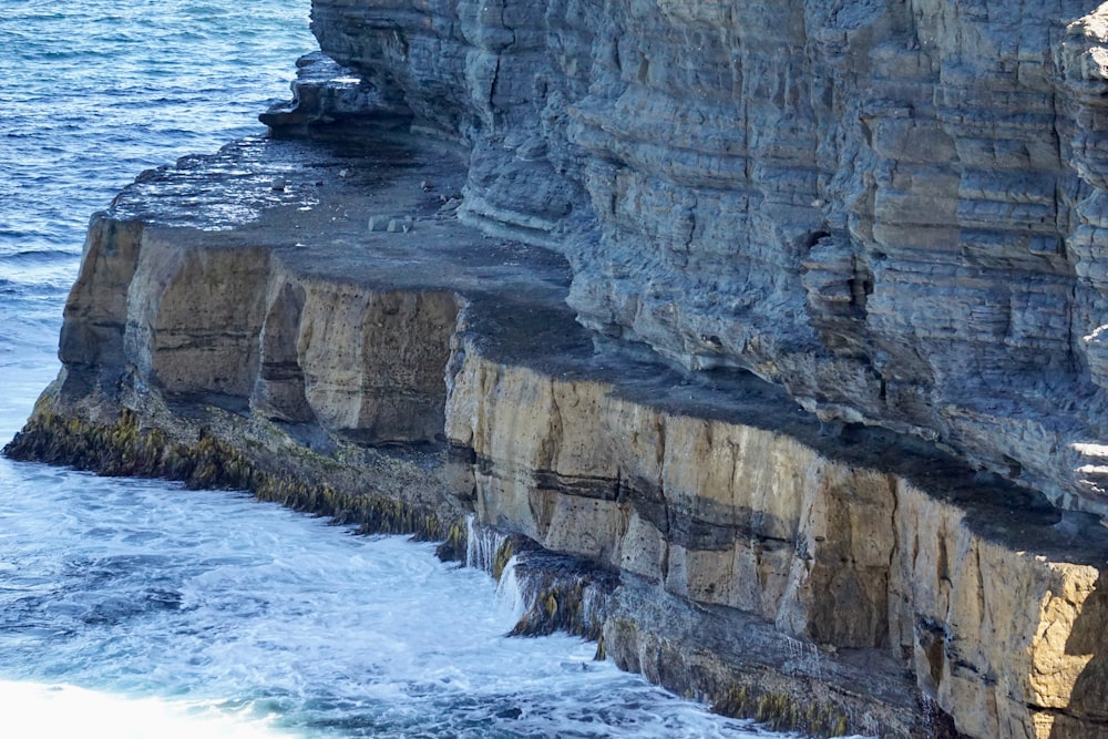 a man standing on the edge of a cliff next to the ocean