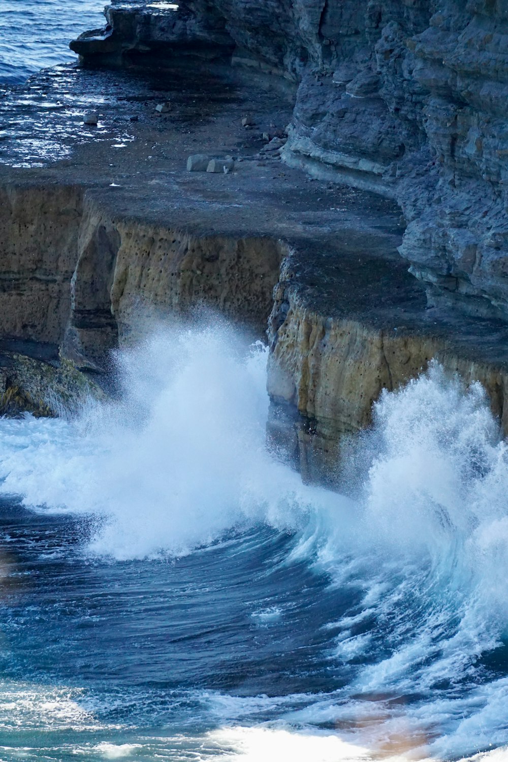 a large wave crashing into a rocky cliff