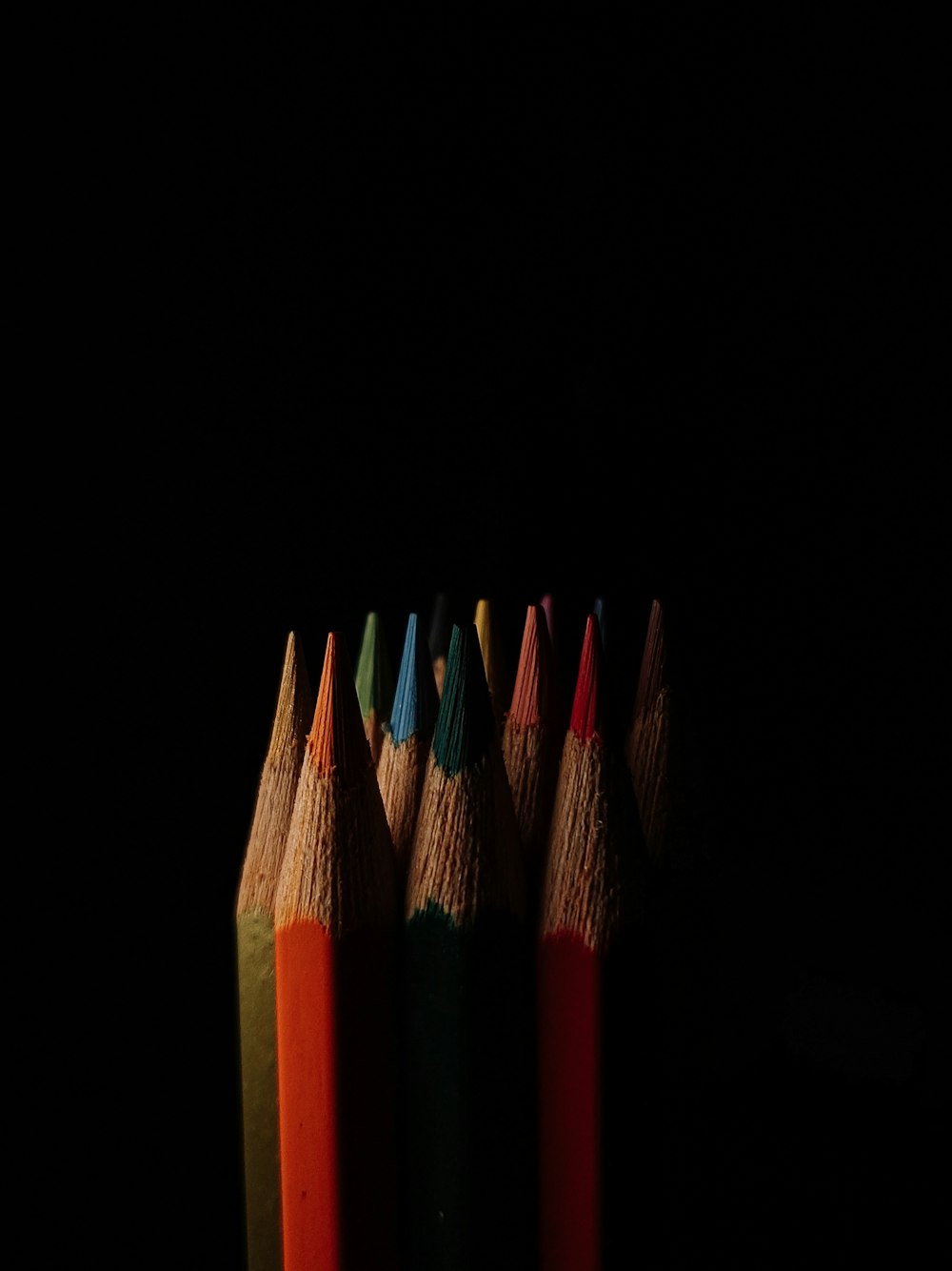 a row of colored pencils sitting on top of a table