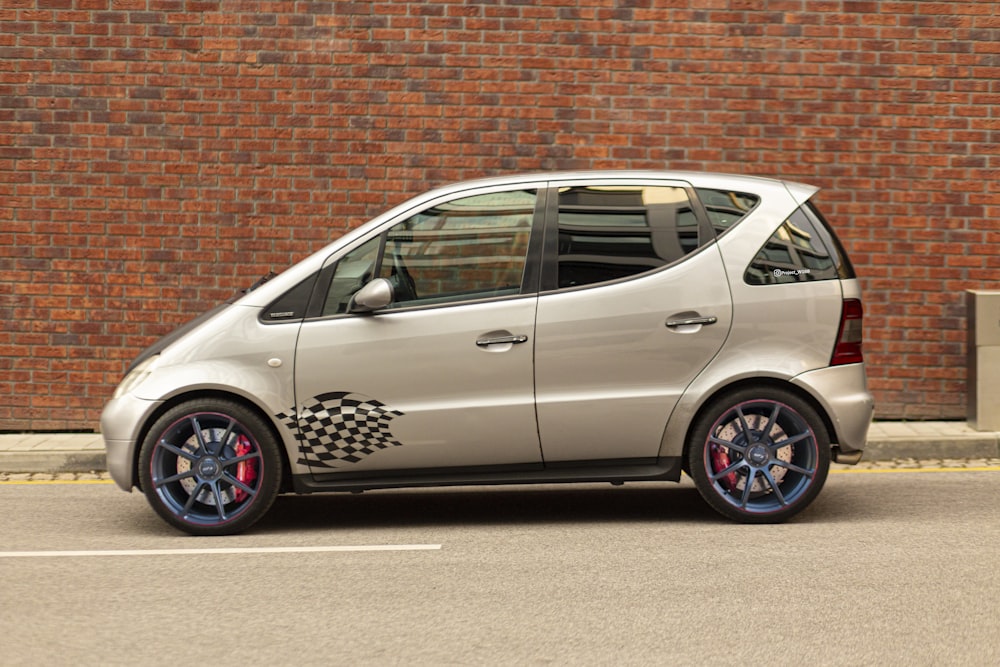 a small silver car parked in front of a brick wall