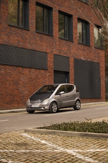 Green compact car parked in front of a modern office building.