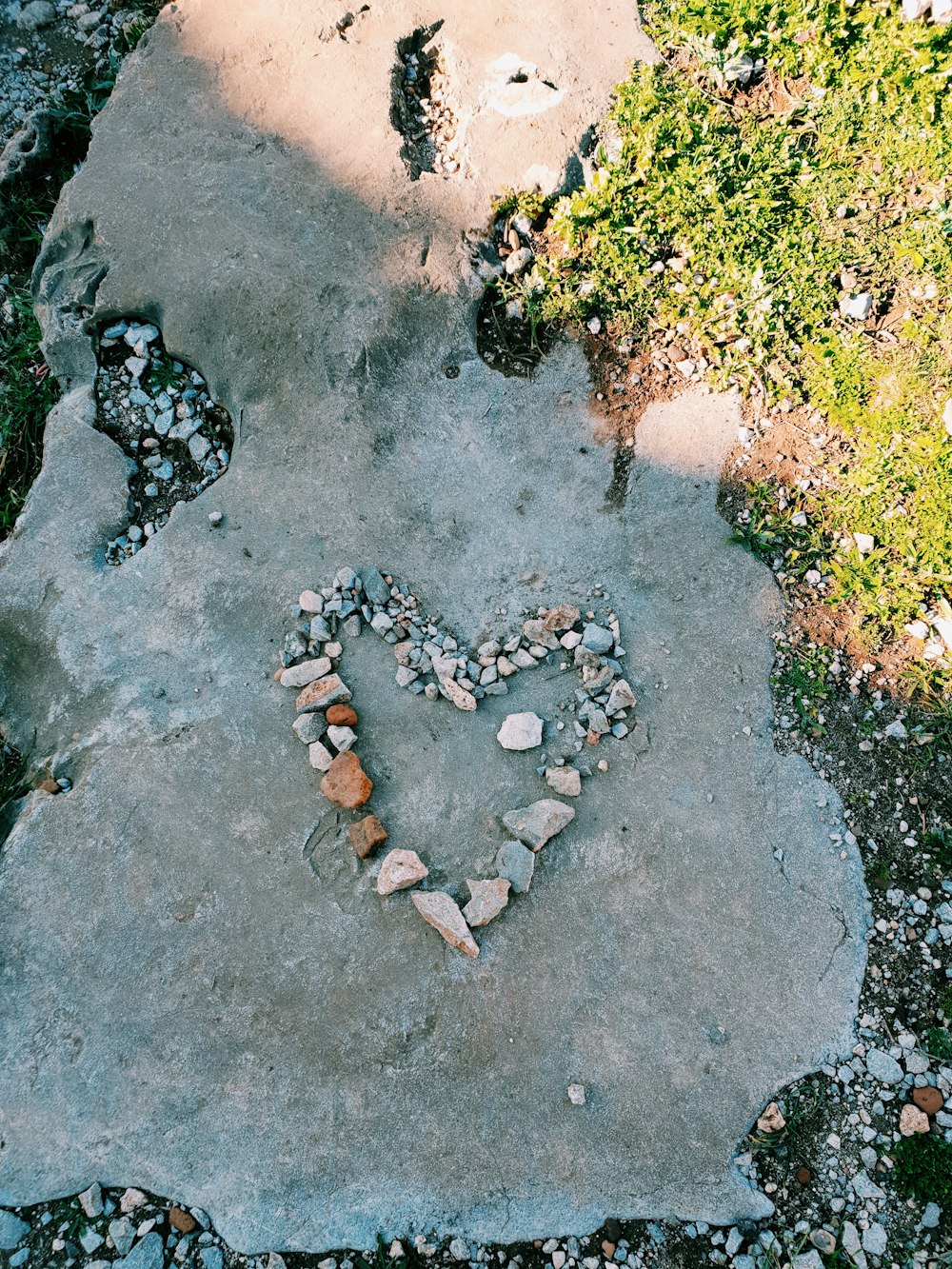 a heart made out of rocks sitting on top of a cement slab
