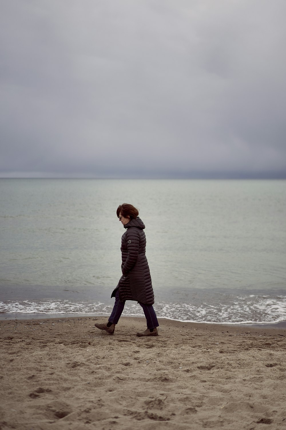 a woman walking on a beach next to the ocean