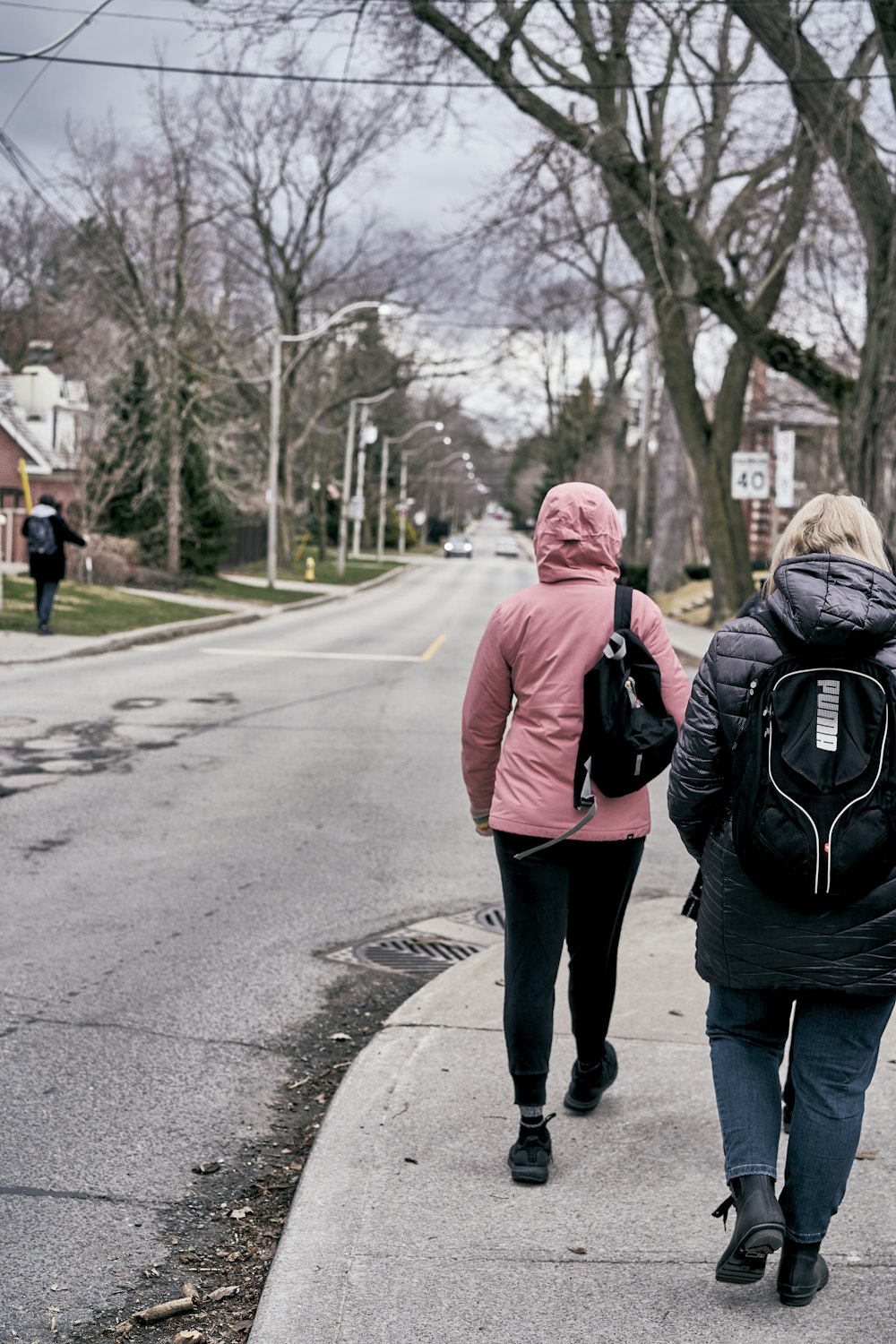 two people walking down a sidewalk with backpacks