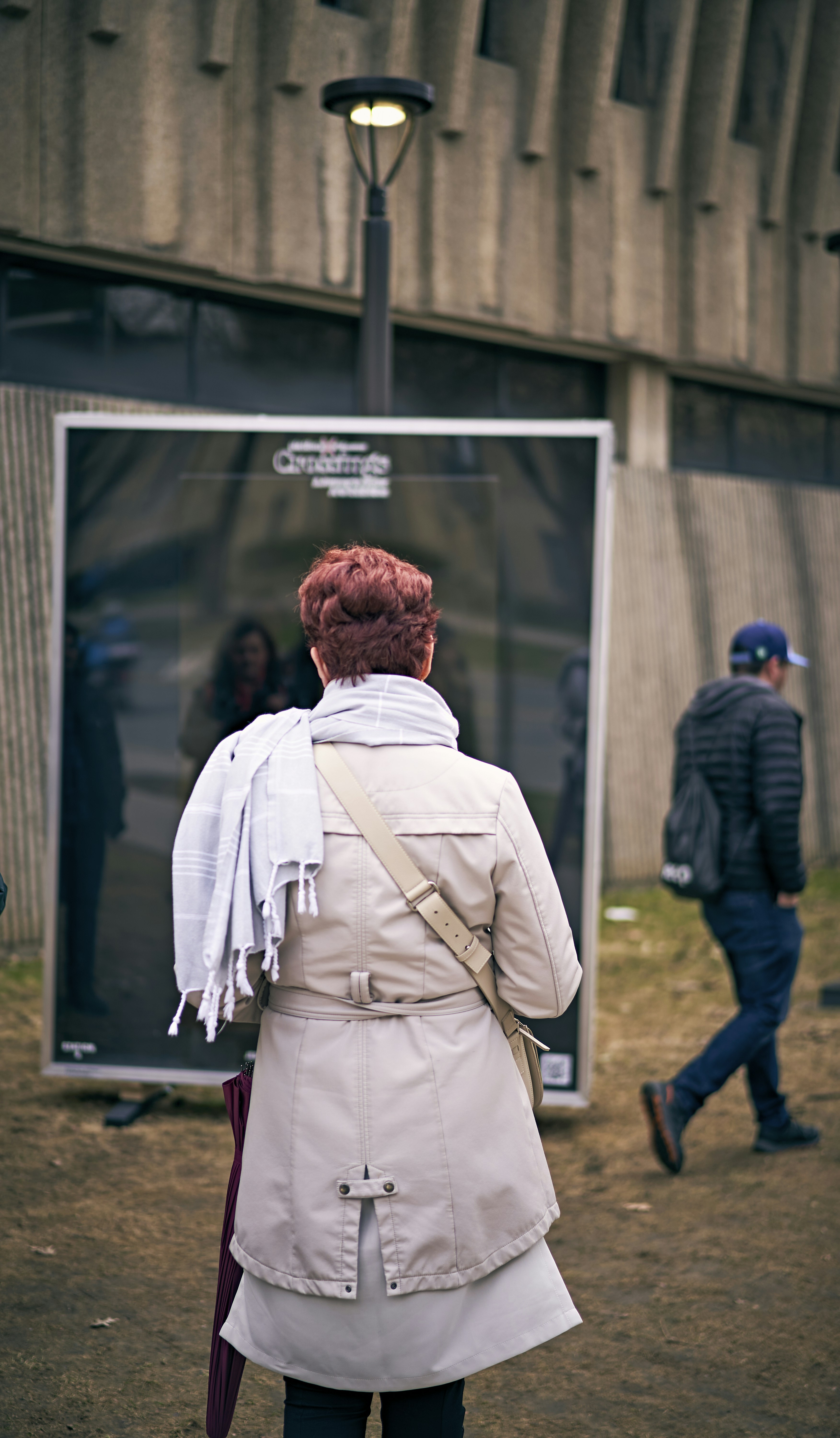 a woman in a trench coat is standing in front of a building