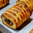 Golden-brown pastries with a flaky crust are arranged on a baking tray. The pastries have a filled center and a scored top, highlighting their texture.