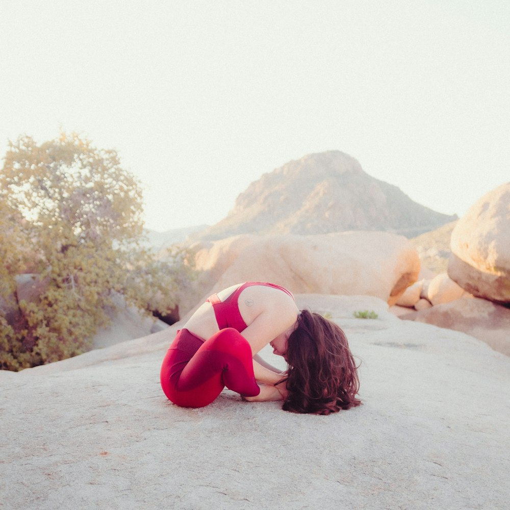 a woman in a red and white bathing suit sitting on a rock