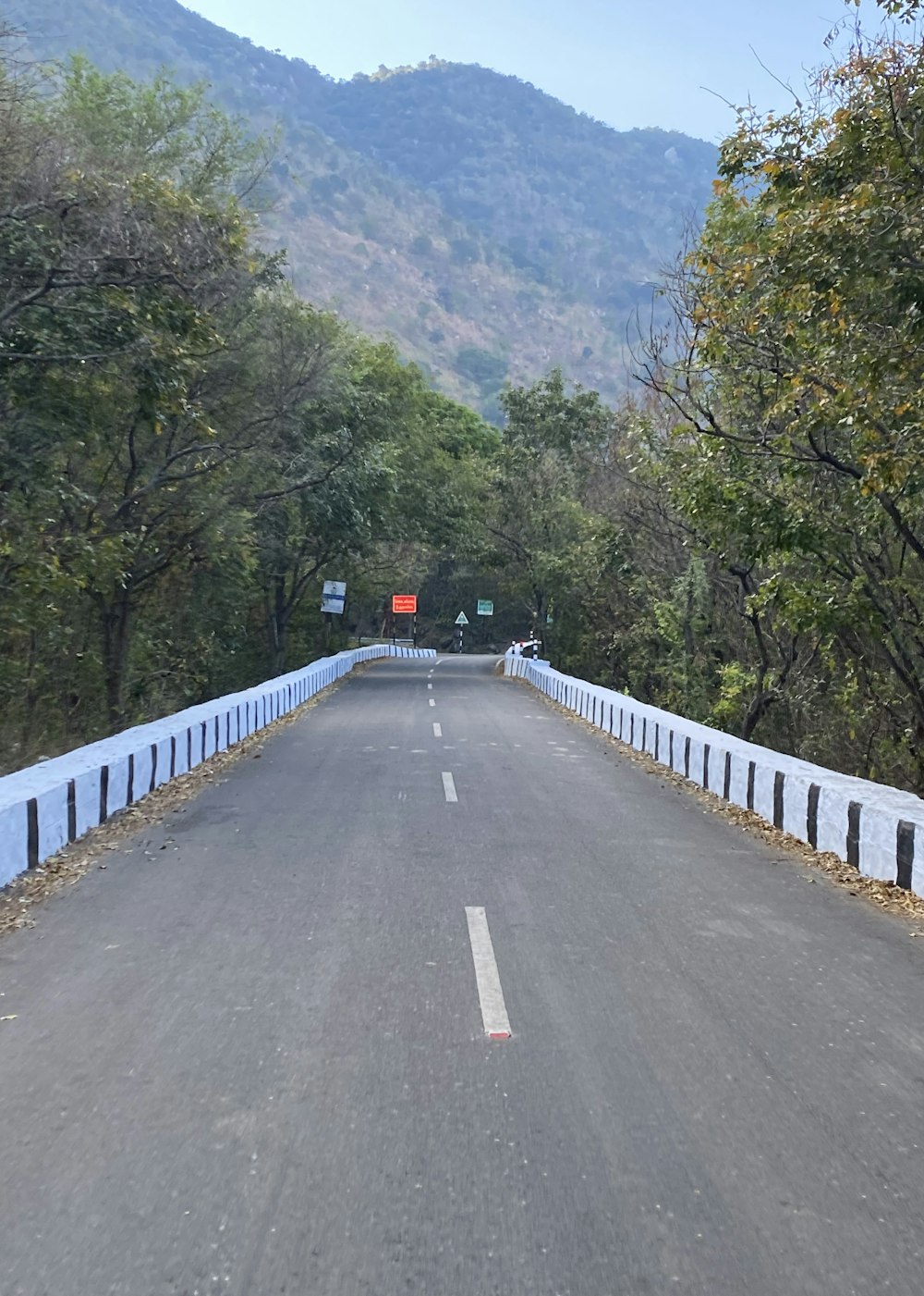an empty road with a white fence and a mountain in the background