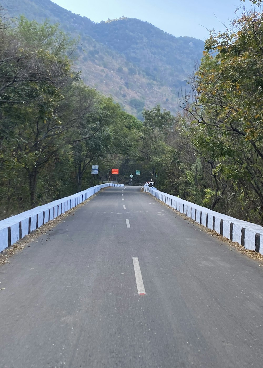 Un camino vacío con una valla blanca y una montaña al fondo