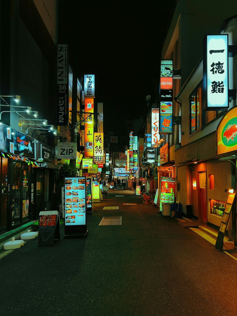 a city street at night with neon signs on the buildings