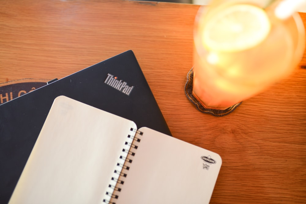 two notebooks sitting on a table next to a candle